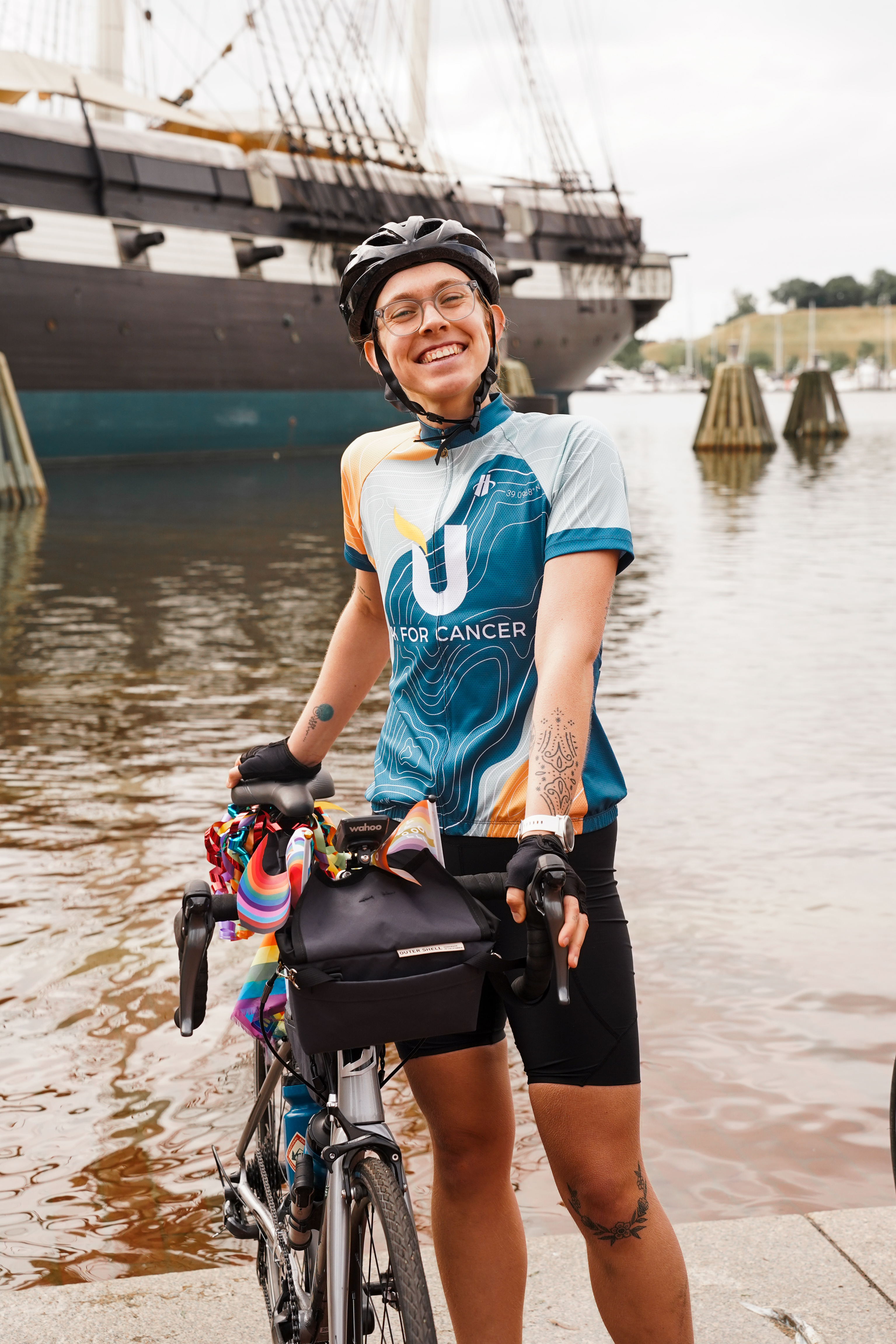 woman wearing bike helmet standing with bike at the baltimore inner harbor